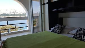 a bedroom with a green bed and a large window at Apartments Kricin 1 in Baška