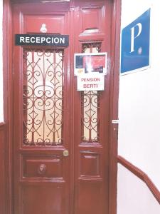 Una puerta roja con una señal. en Pensión Berti Madrid en Madrid