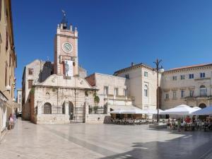 stary budynek z wieżą zegarową na dziedzińcu w obiekcie Latmo Apartment Zadar w mieście Zadar