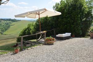 a patio with an umbrella and a couch and a table at Appartamento Crete Senesi in Castelnuovo Berardenga