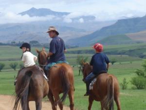 a couple of people riding horses in a field at Silo Cottage in Underberg