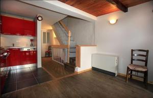 uma cozinha com armários vermelhos e uma escada numa casa em Le Gîte des Faucons em Faucon-de-Barcelonnette