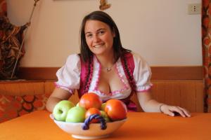 Una donna seduta a un tavolo con un cesto di frutta di Sonnbichl a Rifiano