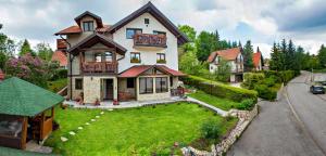 a large white house with a green yard at Apartments Josipovic in Zlatibor
