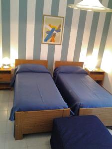 two beds with blue sheets in a bedroom at Hotel Su Giudeu in Chia