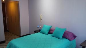 Un dormitorio con una cama verde con almohadas moradas y azules en Edificio Parque Real Habitación con baño privado, en Quito