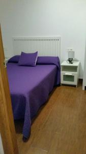 Cama con colcha púrpura y mesita de noche en Apartamentos El Galán, en Carboneras 28 fotos más