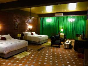 a bedroom with two beds and a green curtain at Golden Lotus Bangalore Boutique Suites in Bangalore