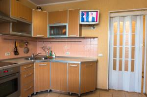 キーロフにあるApartments in Kirov on Maklinaのキッチン(木製キャビネット、壁掛けテレビ付)