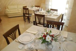 a dining room with tables and chairs with flowers on them at Daphnae House in Palma di Montechiaro