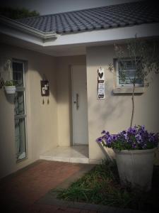 una puerta de entrada de una casa con flores púrpuras en Sharwood Place, en Port Elizabeth