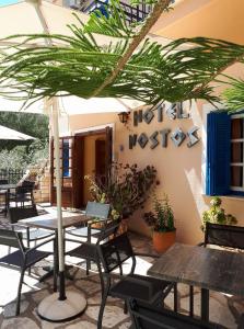 a patio with tables and chairs and a palm tree at Hotel Nostos in Frikes