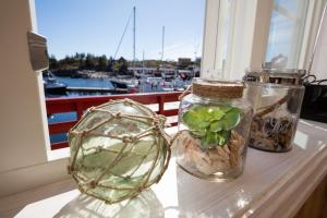 three glass jars sitting on a window sill with a plant in them at The Tide - Rorbuer in Sørvågen