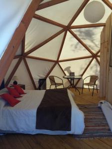 1 dormitorio en una yurta con cama y mesa en Grado8punto8 Glamping Valle de Los Artistas, en Lolol