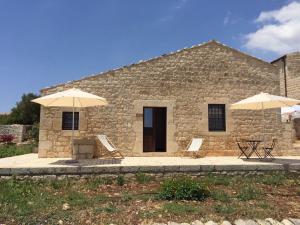 two chairs and umbrellas in front of a building at Agriturismo Arà in Casale Zappulla