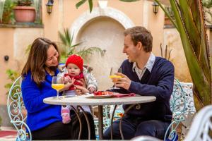 Un uomo e una donna seduti a un tavolo con un bambino di Hotel Emona Aquaeductus a Roma