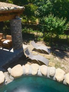 un patio trasero con una piscina con sillas y una pared de piedra en U Fragnu en Omessa