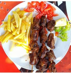 a plate of food with meat and french fries at Arusha Holiday Safari in Arusha