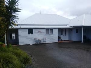 a white house with a table and chairs in a driveway at Harbour Lights Hideaway in Whitianga