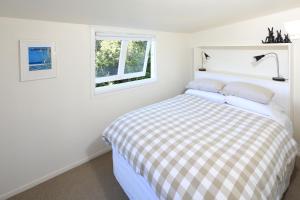 Cape Cottage في Oneroa: غرفة نوم بيضاء بها سرير ونافذة