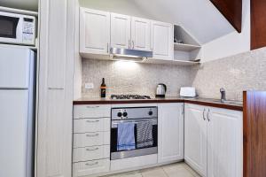 a kitchen with white cabinets and a stove top oven at Fremantle Townhouse Unit 6 in Fremantle