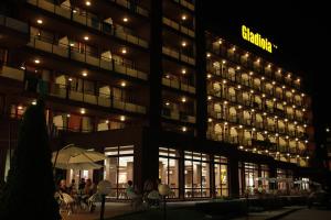 ein Gebäude, vor dem nachts Menschen sitzen. in der Unterkunft Gladiola 3-star in Goldstrand