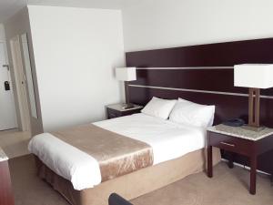 a bedroom with a large bed with a wooden headboard at Airport Gateway Hotel in Auckland