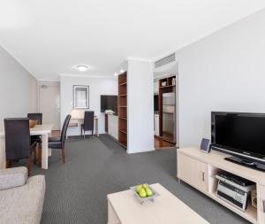 a living room with a flat screen tv and a table at Oaks Brisbane Lexicon Suites in Brisbane