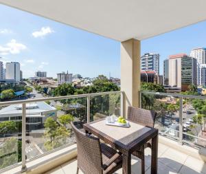 einen Balkon mit einem Tisch und Stühlen sowie Stadtblick in der Unterkunft Oaks Brisbane Lexicon Suites in Brisbane