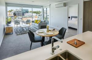 a kitchen and living room with a table and chairs at Swiss-Belsuites Victoria Park Auckland in Auckland