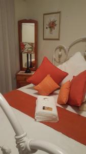 a bed with red and white pillows and a mirror at Harmony Guesthouse in Nelspruit