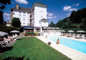 a hotel with a swimming pool and a large building at Hôtel Beauséjour in Chaudes-Aigues