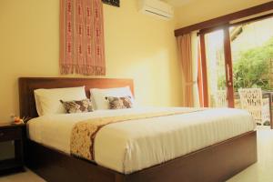 Doremi Ubud Guesthouse في أوبود: غرفة نوم بسرير كبير مع نافذة