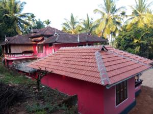 czerwony dom z czerwonym dachem i palmami w obiekcie Spice Garden Farm house w mieście Sultan Bathery