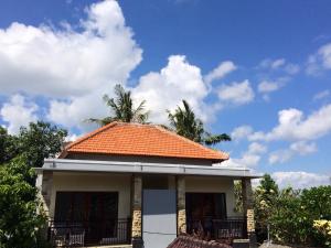 Doremi Ubud Guesthouse في أوبود: سقف من البلاط البرتقالي على منزل به أشجار النخيل
