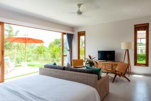 a bedroom with a bed and a couch and a television at Silversand Villa in Tanah Lot