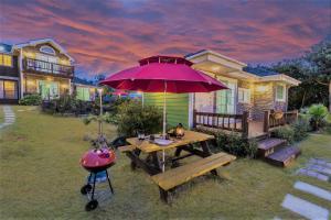 a backyard with a picnic table and a pink umbrella at Jubilee Chalet in Seogwipo