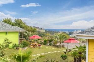 einen Garten mit einem Picknicktisch und roten Sonnenschirmen in der Unterkunft Jubilee Chalet in Seogwipo