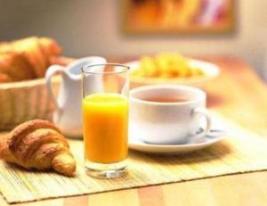 un verre de jus d'orange et une tasse de café sur une table dans l'établissement La Terrasse des Oliviers, à Mansigné