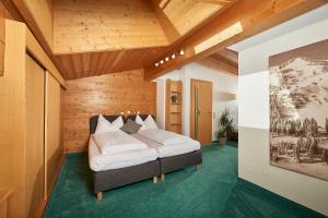 ein Schlafzimmer mit einem Bett in einem Zimmer mit Holzdecken in der Unterkunft Landhaus Zirmhof in Saalbach-Hinterglemm