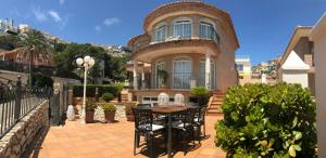 Villa Cap Blanc Beach Cullera في فارو دي كوييرا: منزل أمامه طاولة وكراسي