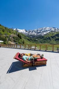 a group of people laying on a bed on a patio at Berghotel Trübsee in Engelberg