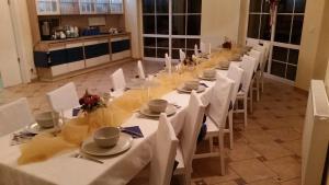 a long table with white tables and white chairs at Villa Nobis in Łeba