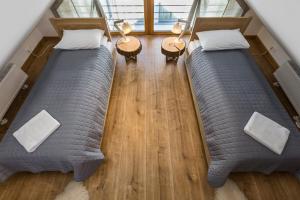 two beds in the middle of a room with wood floors at Smrekowa Polana Resort & Spa in Zakopane