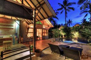 an outdoor patio with a deck and a swimming pool at Villas SAMALAMA Gili Air in Gili Air