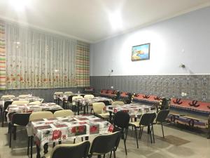 a room full of tables and chairs with red and white table cloth at Bereke Hostel in Shymkent