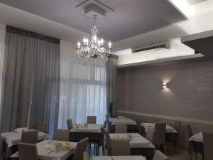 a dining room with white tables and a chandelier at Albergo Paris in Sottomarina