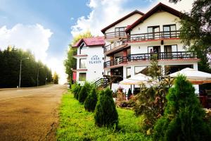 ein großes weißes Gebäude an der Seite einer Straße in der Unterkunft Casa Vlasin in Poiana Brașov