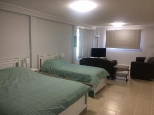 Pokój z 2 łóżkami, krzesłem i kanapą w obiekcie Stretton Lane w mieście Townsville