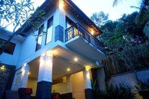 a white house with a balcony with lights on it at Griya Shanti Villas & Spa in Ubud